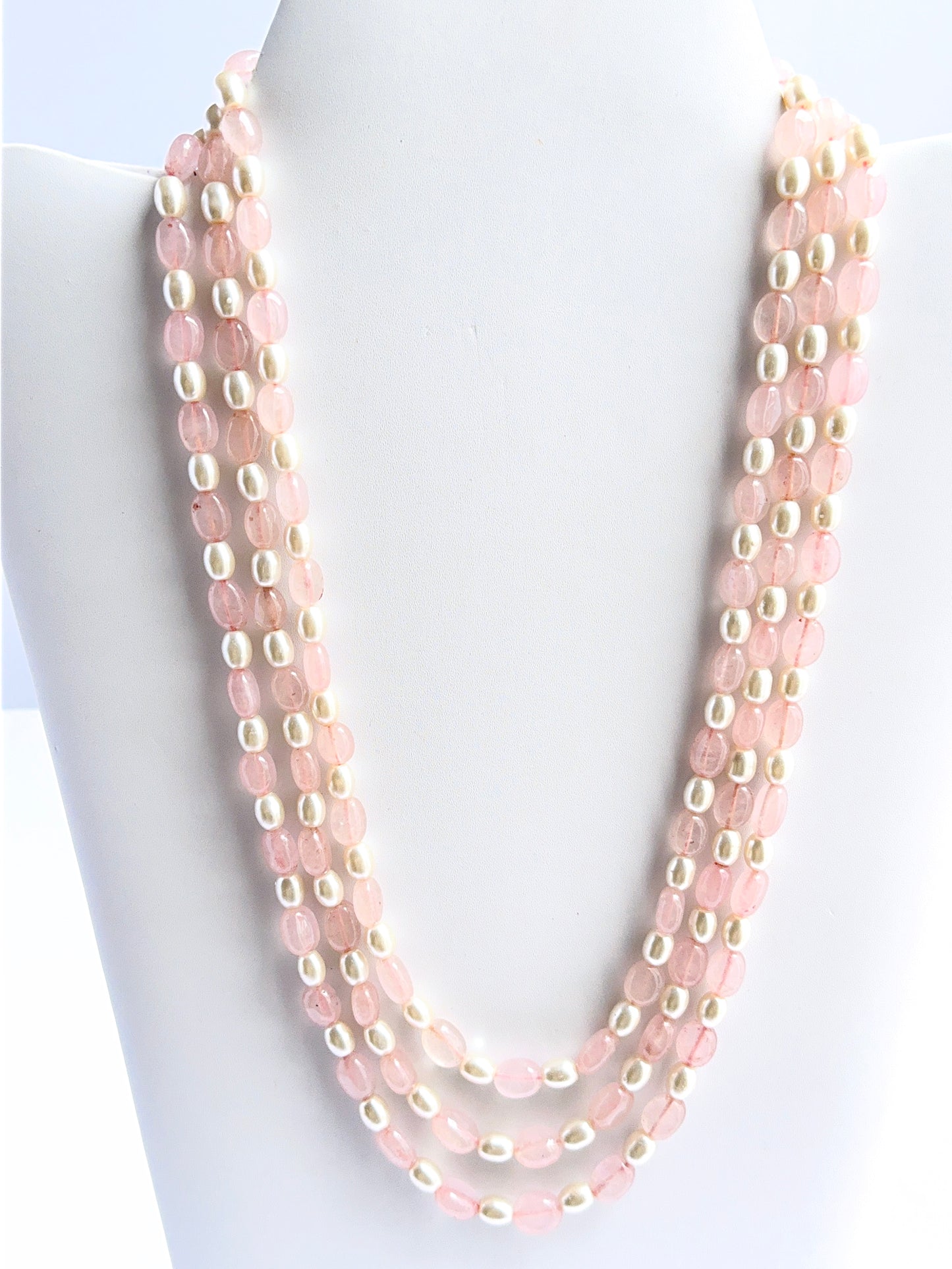 Three‑strand quartz and shell pearl necklace featuring smooth oval beads in a bold layered design.