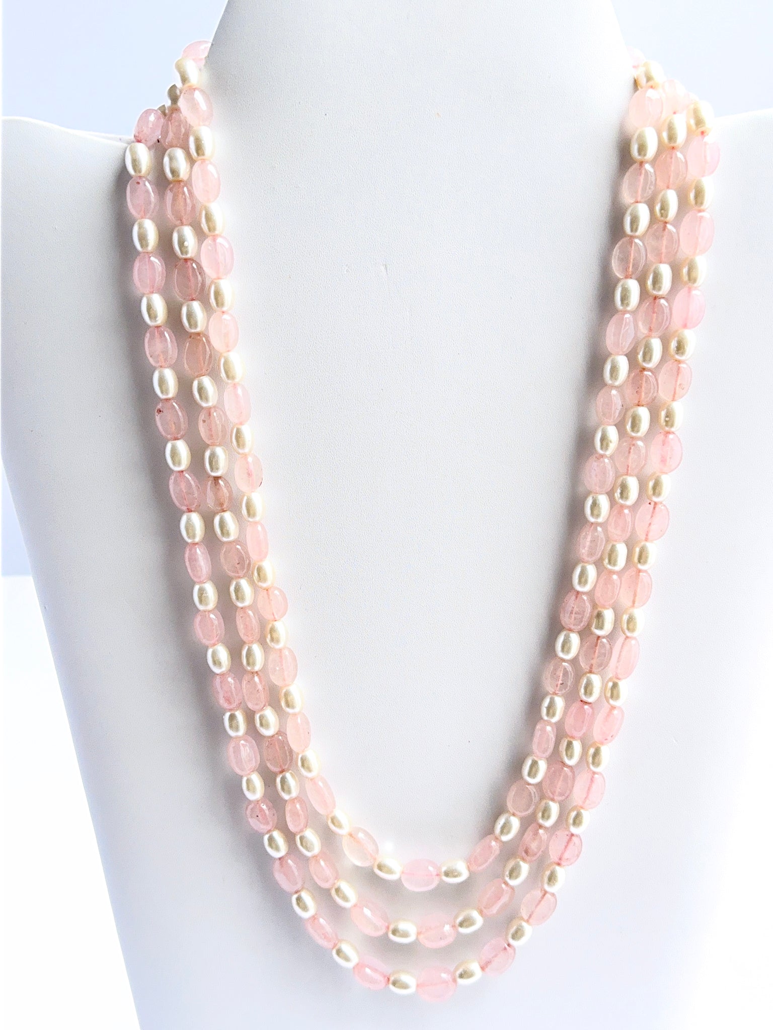 Three‑strand quartz and shell pearl necklace featuring smooth oval beads in a bold layered design.