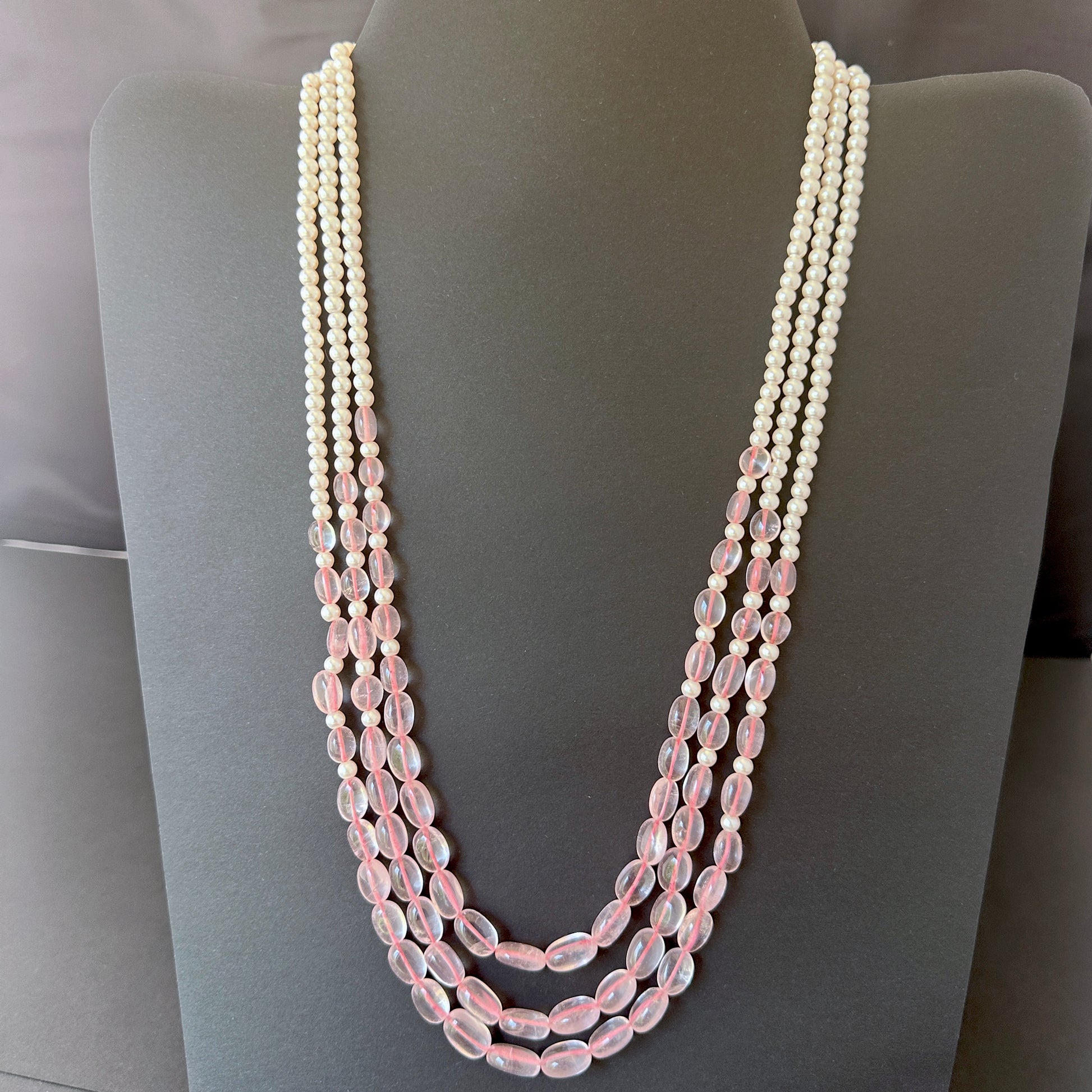 Three-strand necklace with rose quartz ovals and shell pearls in soft pink and white hues.