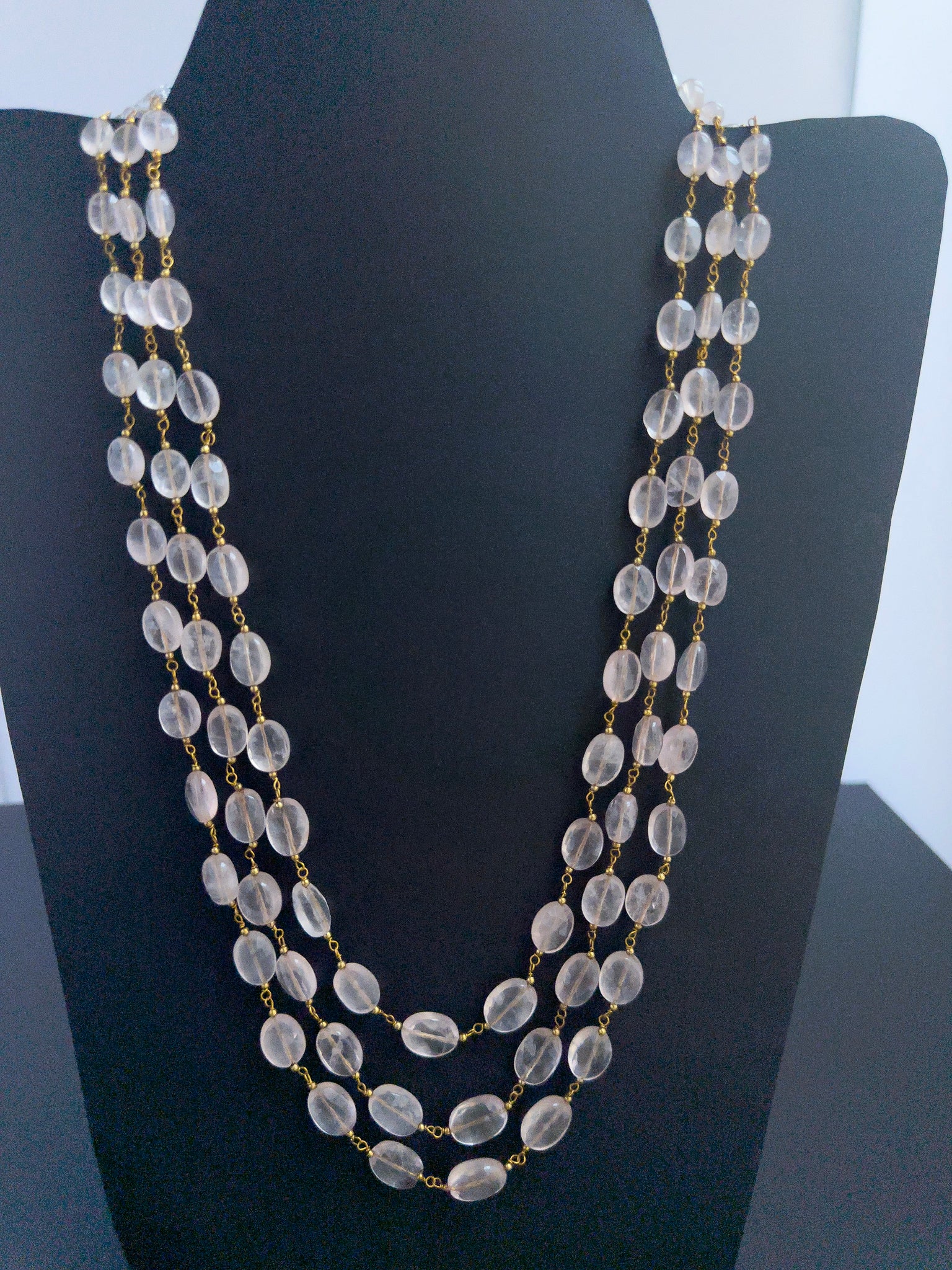 Close-up of Strawberry Quartz gemstone beads, faceted oval cut, shimmering brilliance, arranged in strands.