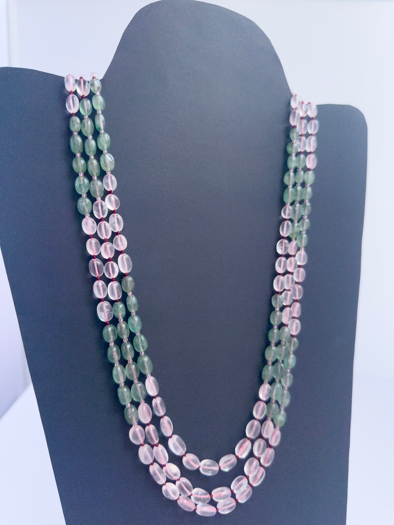 Close-up of Quartz gemstone beads, smooth oval cut, polished finish, arranged in strands.