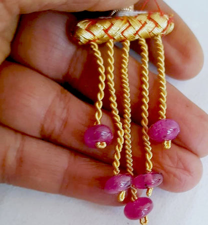 A person holds delicate strands of ruby beads, showcasing their smooth design.