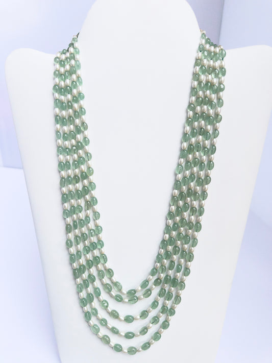 Close-up of quartz and shell pearl beads, polished oval cut, arranged in multiple strands.