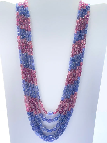 Five‑strand ruby and tanzanite necklace featuring smooth oval beads in vibrant jewel tones.