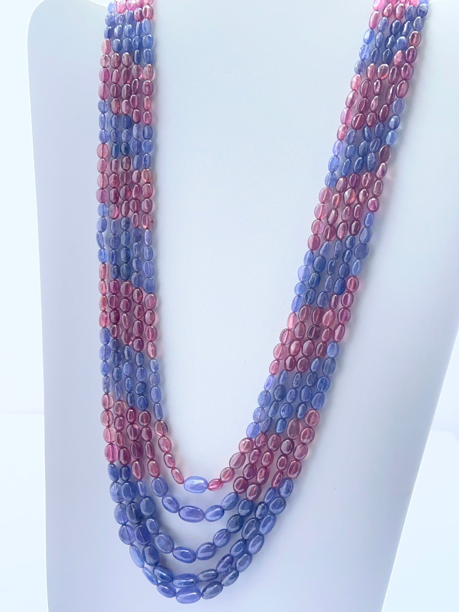 Close‑up of ruby and tanzanite oval beads arranged on a luxurious multi‑strand necklace.