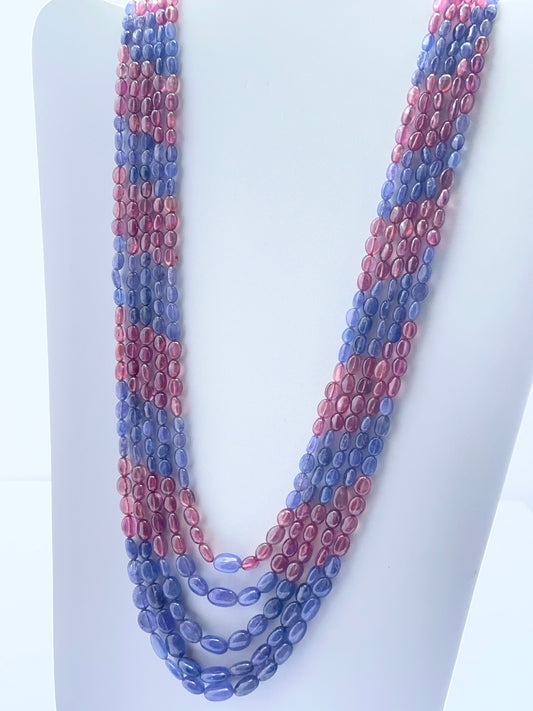 Close‑up of ruby and tanzanite oval beads arranged on a luxurious multi‑strand necklace.