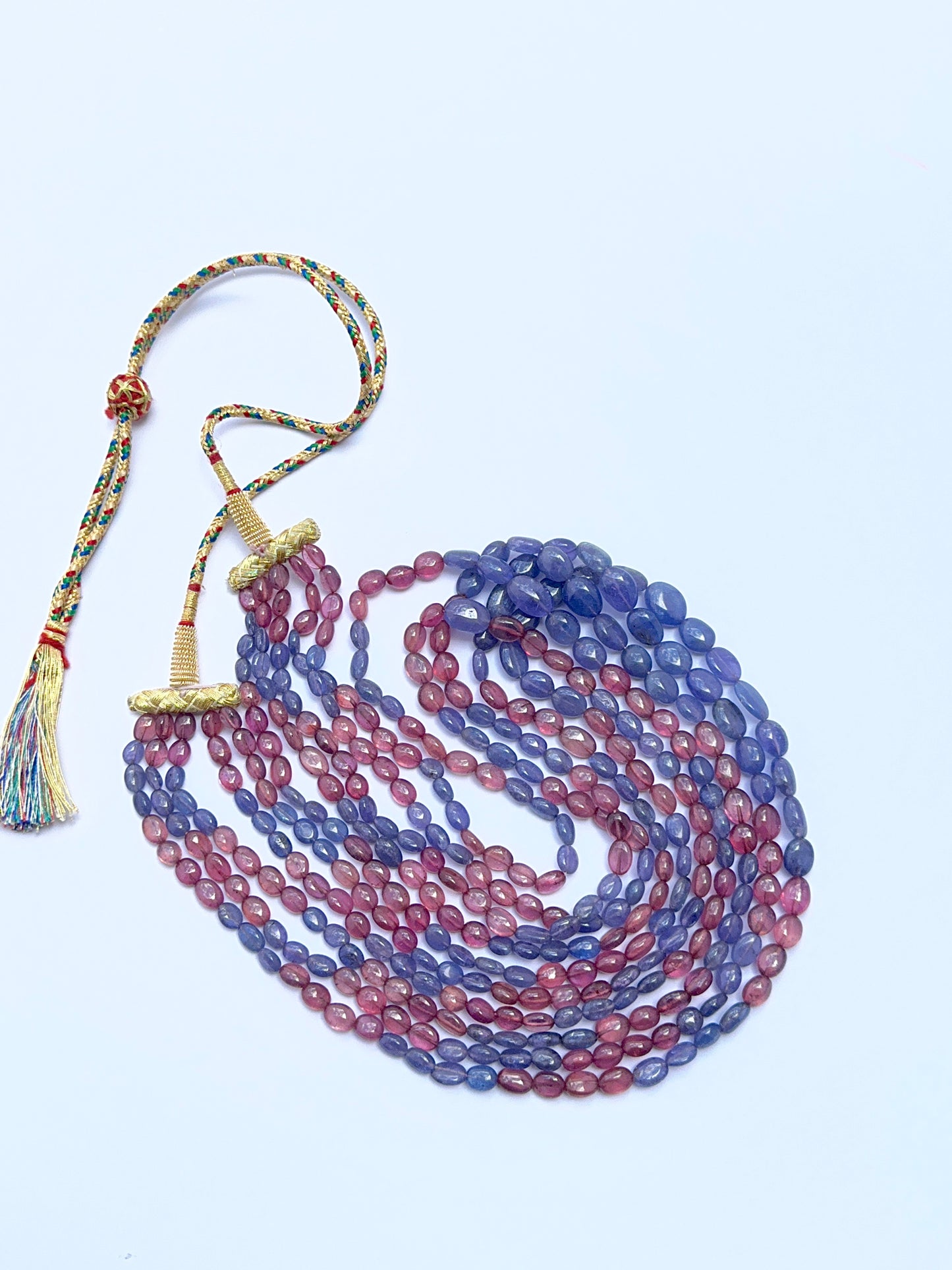 Elegant five‑strand gemstone necklace featuring polished ruby and tanzanite beads.