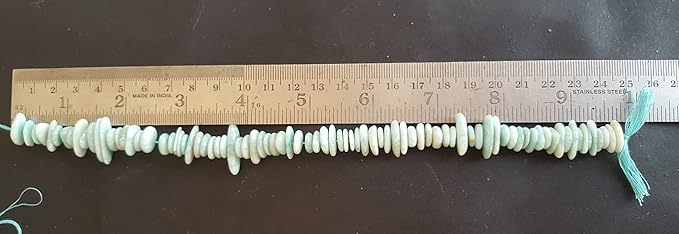 Close-up of a ruler alongside green amazonite beads, showcasing their shape and size.