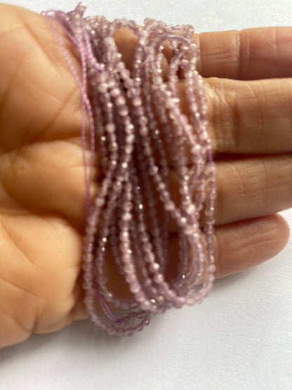 A hand displays a beautiful purple faceted rondelle amethyst gemstone beads, emphasising its faceted design and vibrant colour.