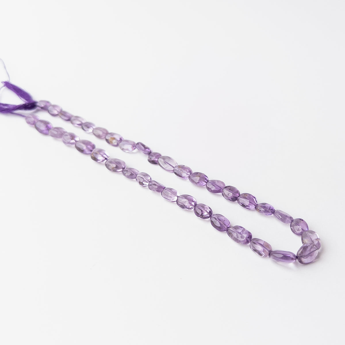 Genuine Amethyst gemstone beads arranged on a 32cm strand with vibrant violet tones and premium quality.