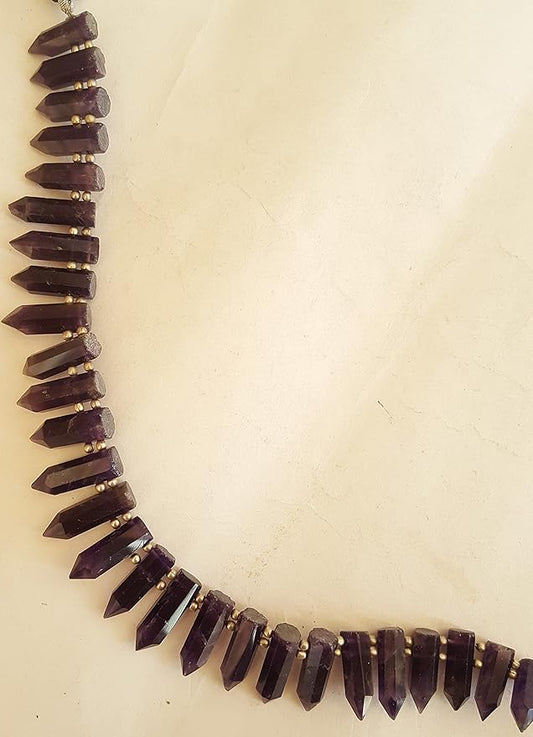  A close-up of a strand featuring purple beads displayed on a sleek white surface, highlighting its vibrant colour contrast.