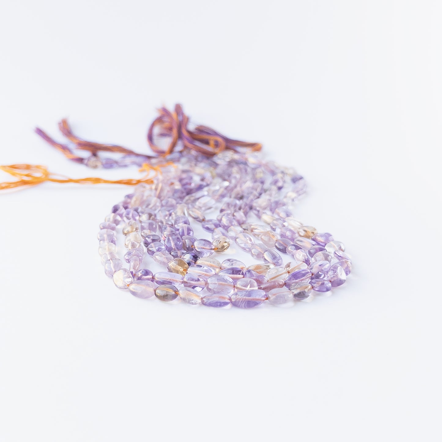 Close‑up of Ametine smooth tumble beads showing their lustre, organic shaping and elegant colour mix.