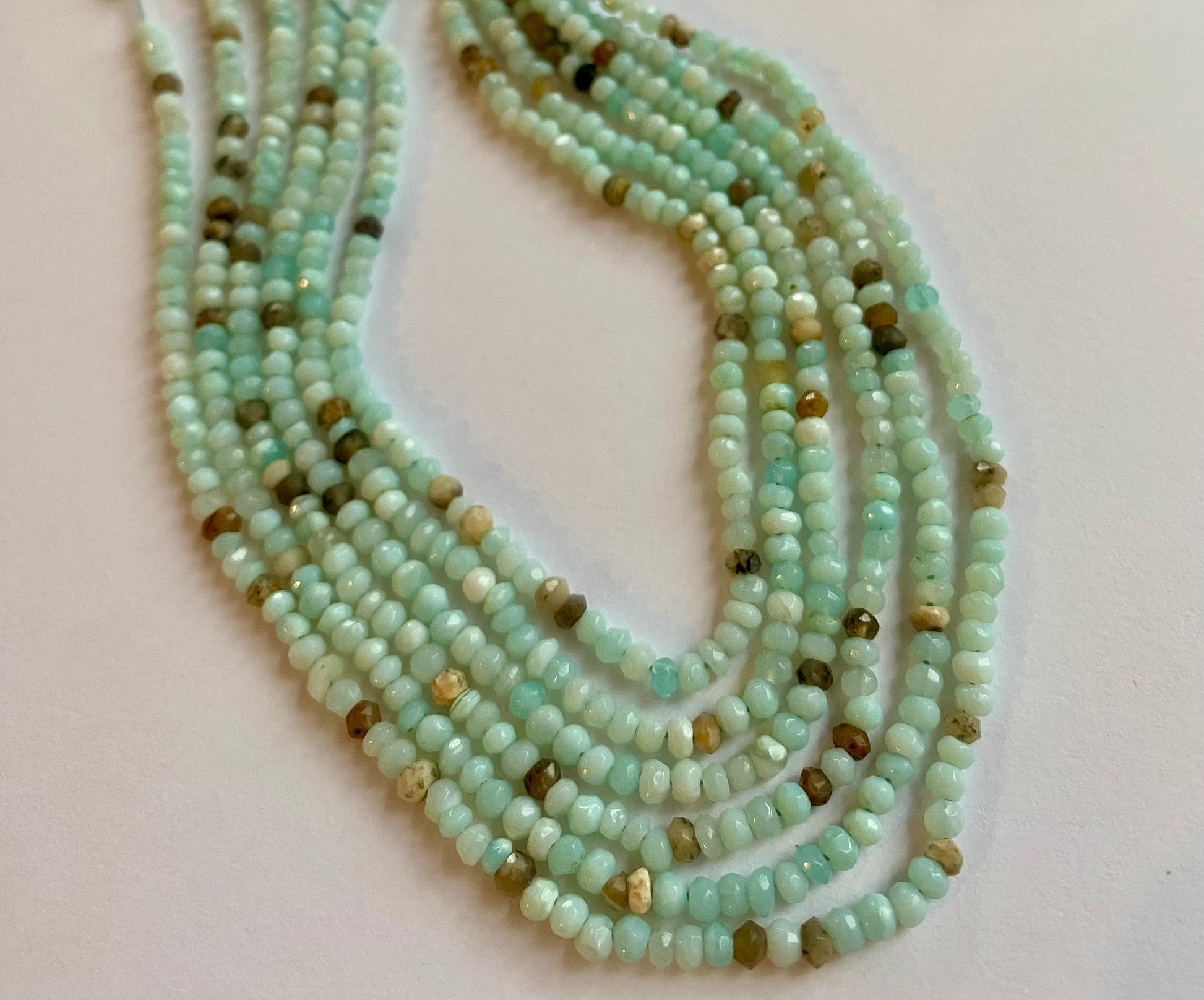 Elegant gemstone strand adorned with 3-3.5mm smooth white opal beads, highlighting the beauty of aqua sea opals.