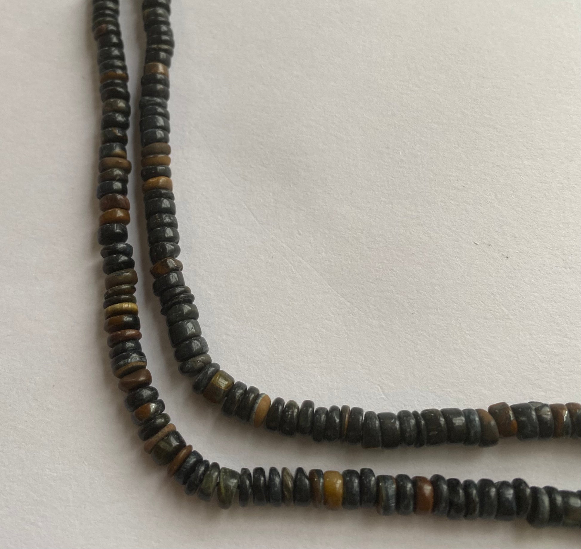  A striking strand with black tiger eye 5-5.5mm beads resting on a white surface, showcasing the vivid colours and elegant design.