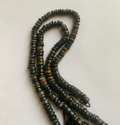  A close-up of a strand featuring black tiger eye beads displayed on a sleek white surface, highlighting its vibrant colour contrast.