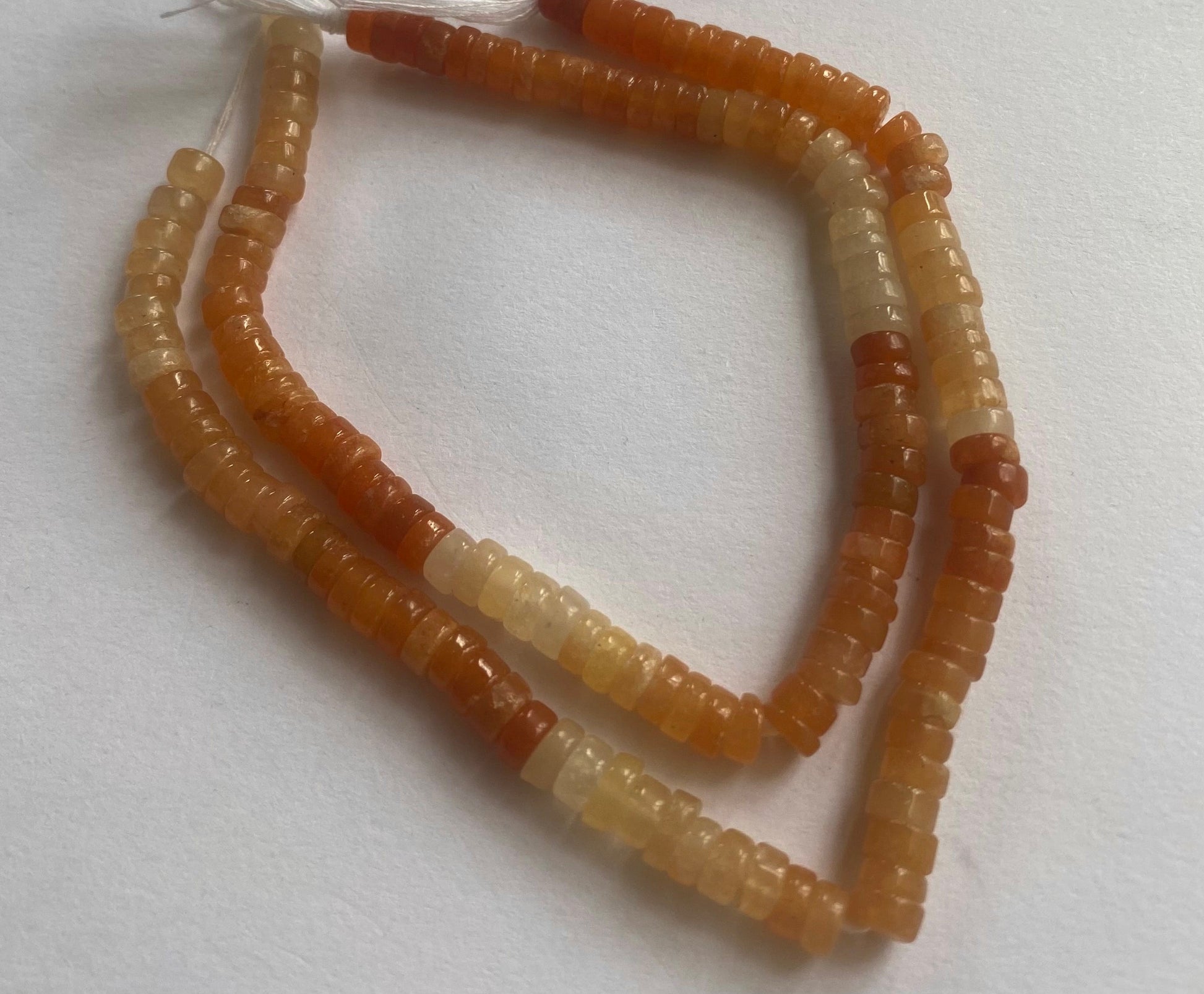 A close-up of a strands of smooth heishi carnelian beads, measuring 5.5mm, highlighting their rich, vibrant hue.  