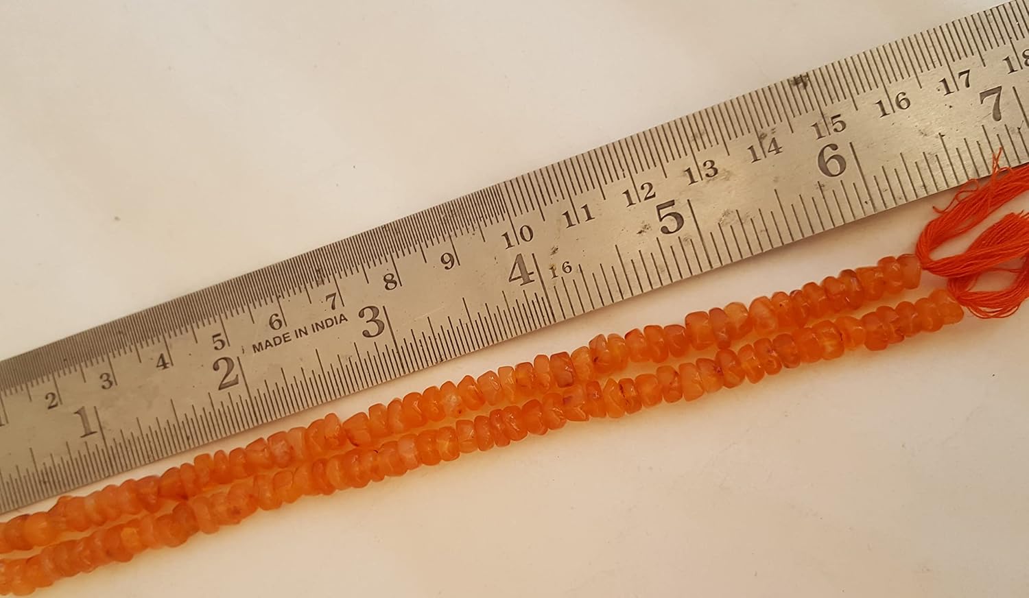 An 6mm carnelian natural stone smooth wheel bead next to a ruler for size reference.