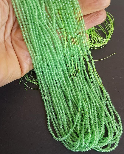  A persons hand showing the close-up of multiple strands of green chalcedony beads, 2.5mm in size, highlighting their faceted rondelle design and rich hue.
