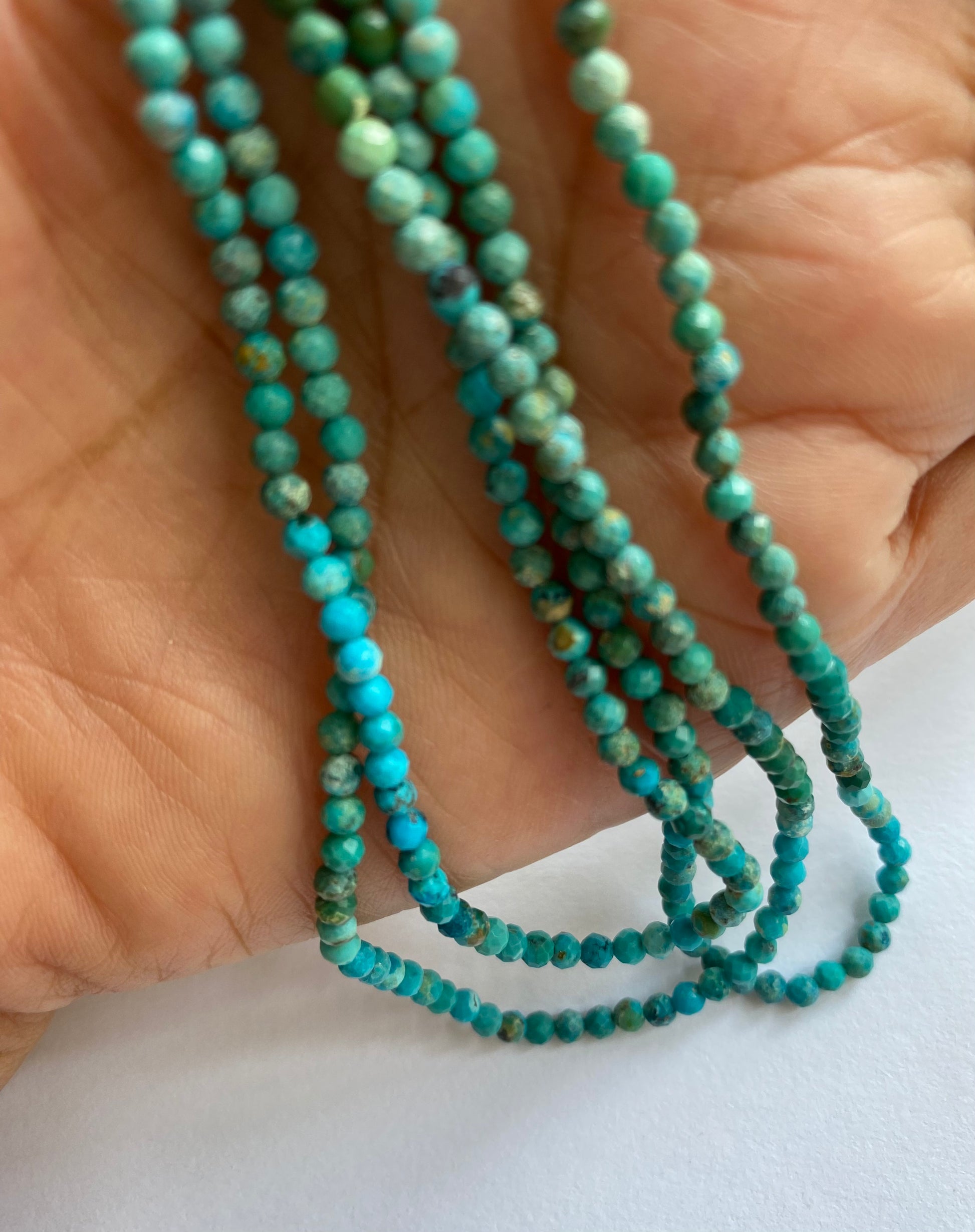 A strand of Chrysocolla beads, featuring 3mm, faceted rondelle shapes, showcasing their vibrant colour and shine.