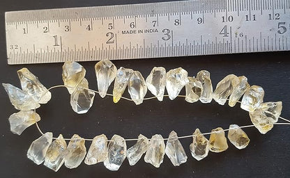A ruler beside a cluster of yellow citrine gemstone beads, measuring 9mm to 10mm in size.