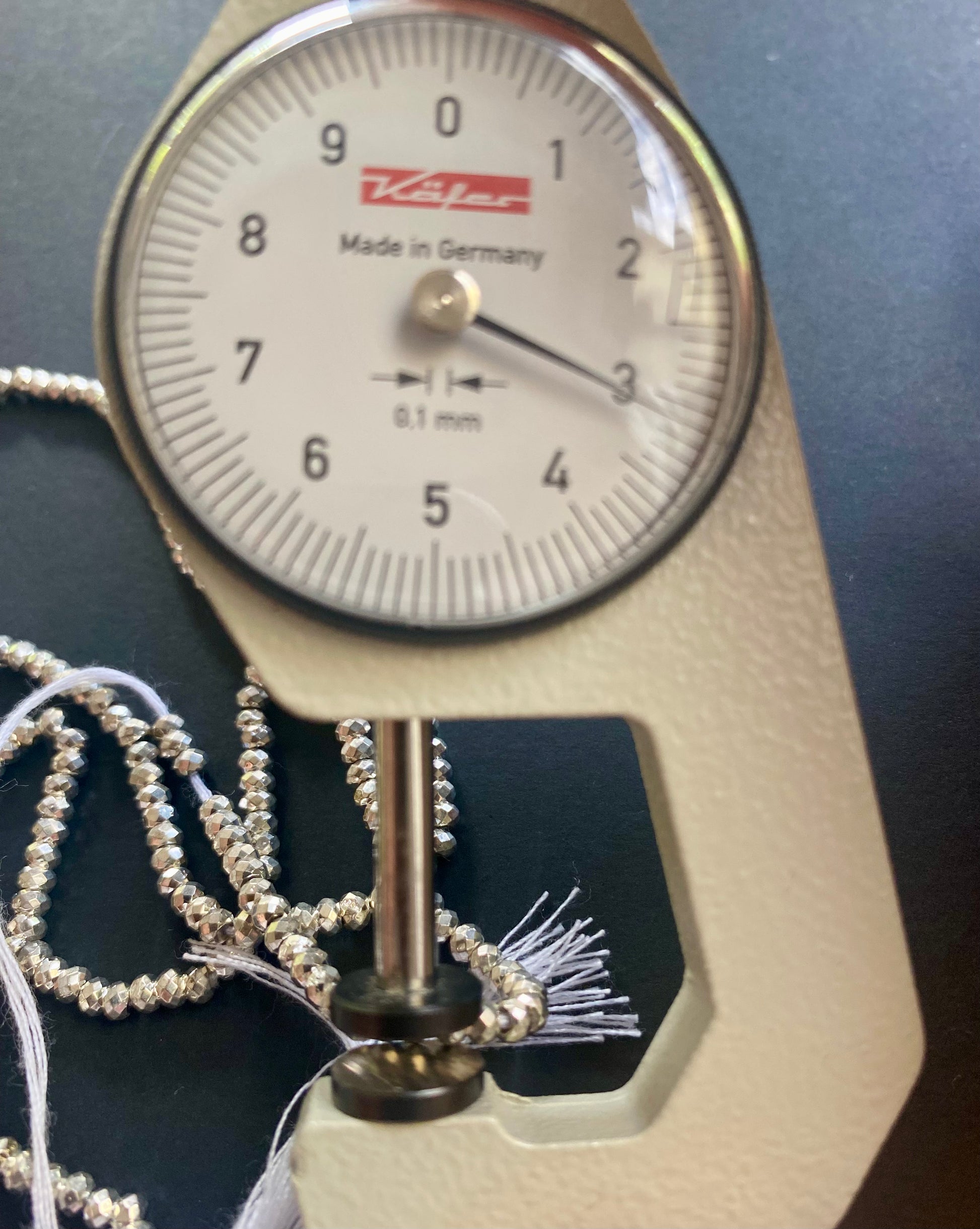 A dial gauge displaying a delicate 3.1mm pyrite strand, highlighting size and measurement.