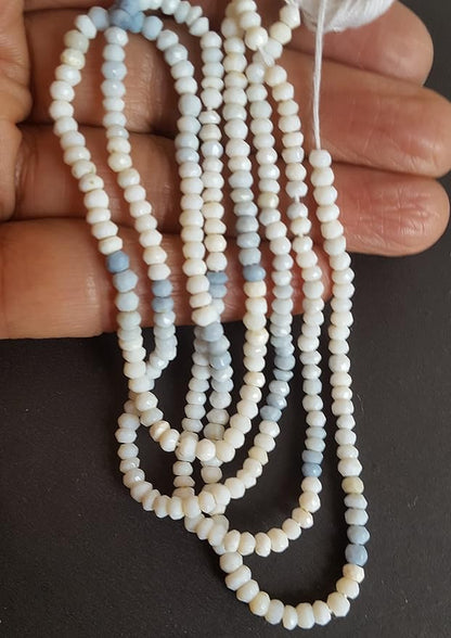 Close-up of a person’s hand holding a strand of denim opal beads, highlighting their unique faceted design.
