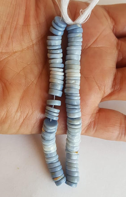 Close-up of a person holding a colourful gemstone strand made with Denim Opal Heishi smooth wheel beads, showcasing its vibrant design.