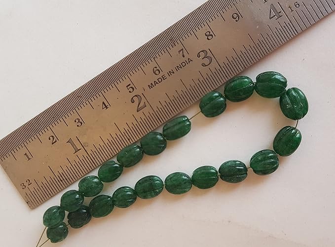 Close-up of a ruler alongside green Emerald beads, showcasing their shape and size.