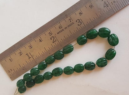 Close-up of a ruler alongside green Emerald beads, showcasing their shape and size.