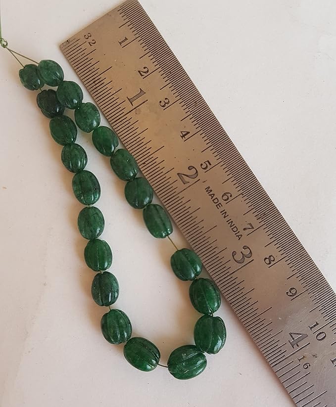 A ruler and green Emerald beads are displayed closely, highlighting the beads' carved oval design.