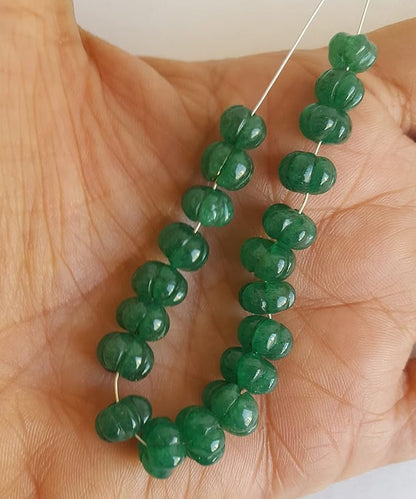  A close-up of a strand of green Emerald beads highlighting their carved rondelle design and rich hue.