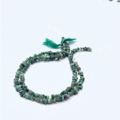 Close-up of gemstone beads highlighting emerald’s raw beauty and unique chip shapes.