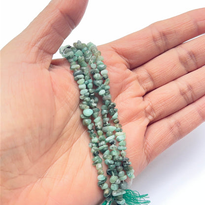 A person holds delicate strands of emerald beads, showcasing their smooth design