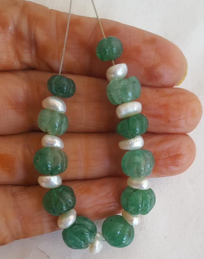 A person holding a strand of emerald green beads and pearls, showcasing carved rondelle beads ranging from 7mm to 10mm.