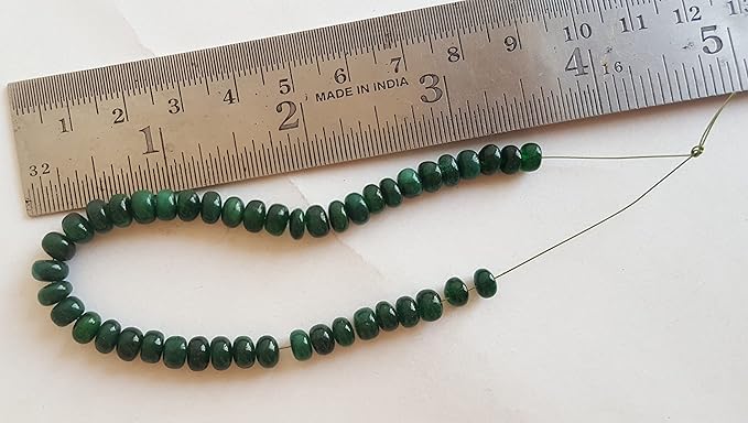 A ruler beside a smooth emerald natural gemstone bead, measuring 5-6mm in diameter.
