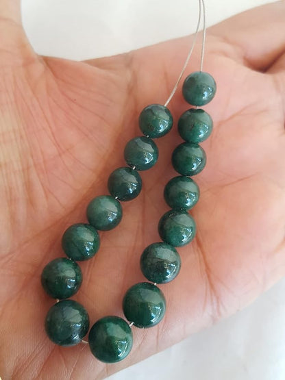 A hand displays a strand of beautiful green emerald natural gemstone beads, highlighting their smooth texture and rondelle design.