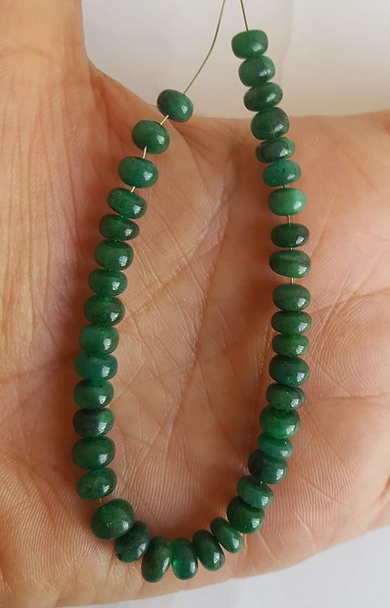A person holding a strand of smooth green emerald beads, showcasing the colour and rondelle shape.