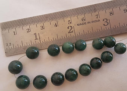 A ruler beside a smooth emerald natural gemstone bead, measuring 8-9mm in diameter.
