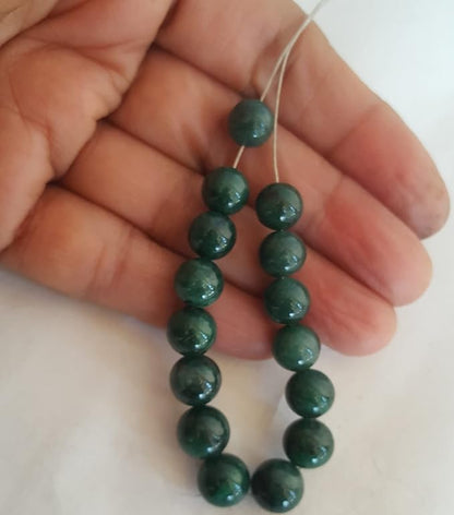 Close-up of a person grasping a strand of emerald gemstone beads, each rondelle measuring 8-9mm in size.
