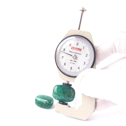 A dial gauge measures the Emerald smooth tumble 22mm × 16.6–17.7mm gemstone.