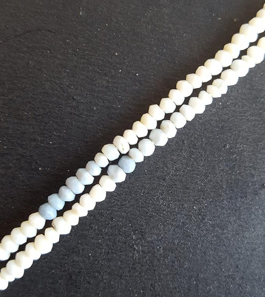A strand of faceted rondelle denim opal beads in white and blue, elegantly displayed on a black surface.