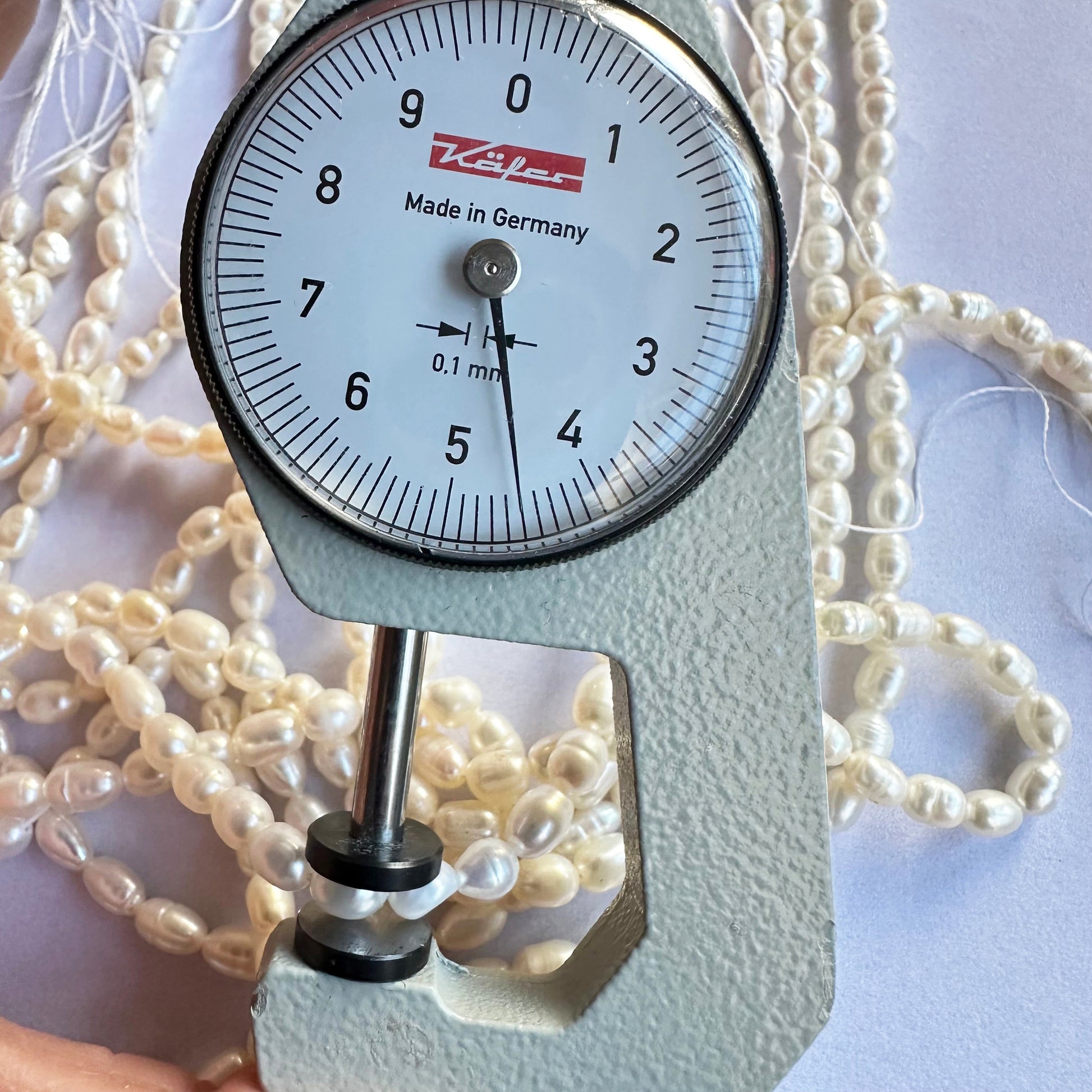 A dial gauge measures the Fresh Water Pearl smooth fancy shape 4mm to 4.5mm gemstone, ensuring size accuracy.