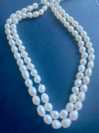 Beautiful strand of 6mm freshwater pearl beads resting on a sleek black background, showcasing their lustre.