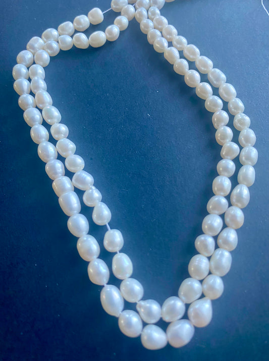 Beautiful strand of 6mm freshwater pearl beads resting on a sleek black background, showcasing their lustre.