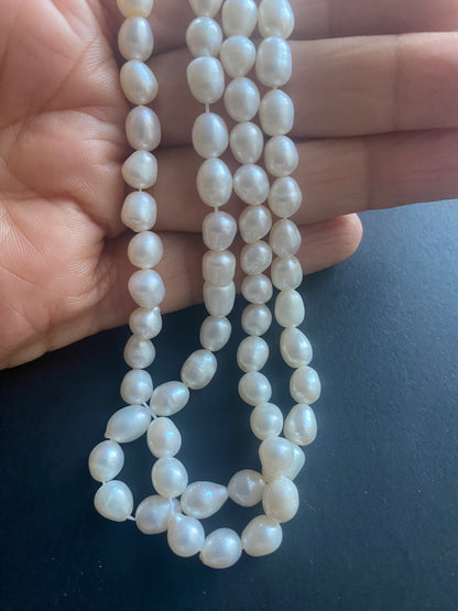 A hand delicately holds a strand of 6mm freshwater pearls, showcasing their lustre and elegance.