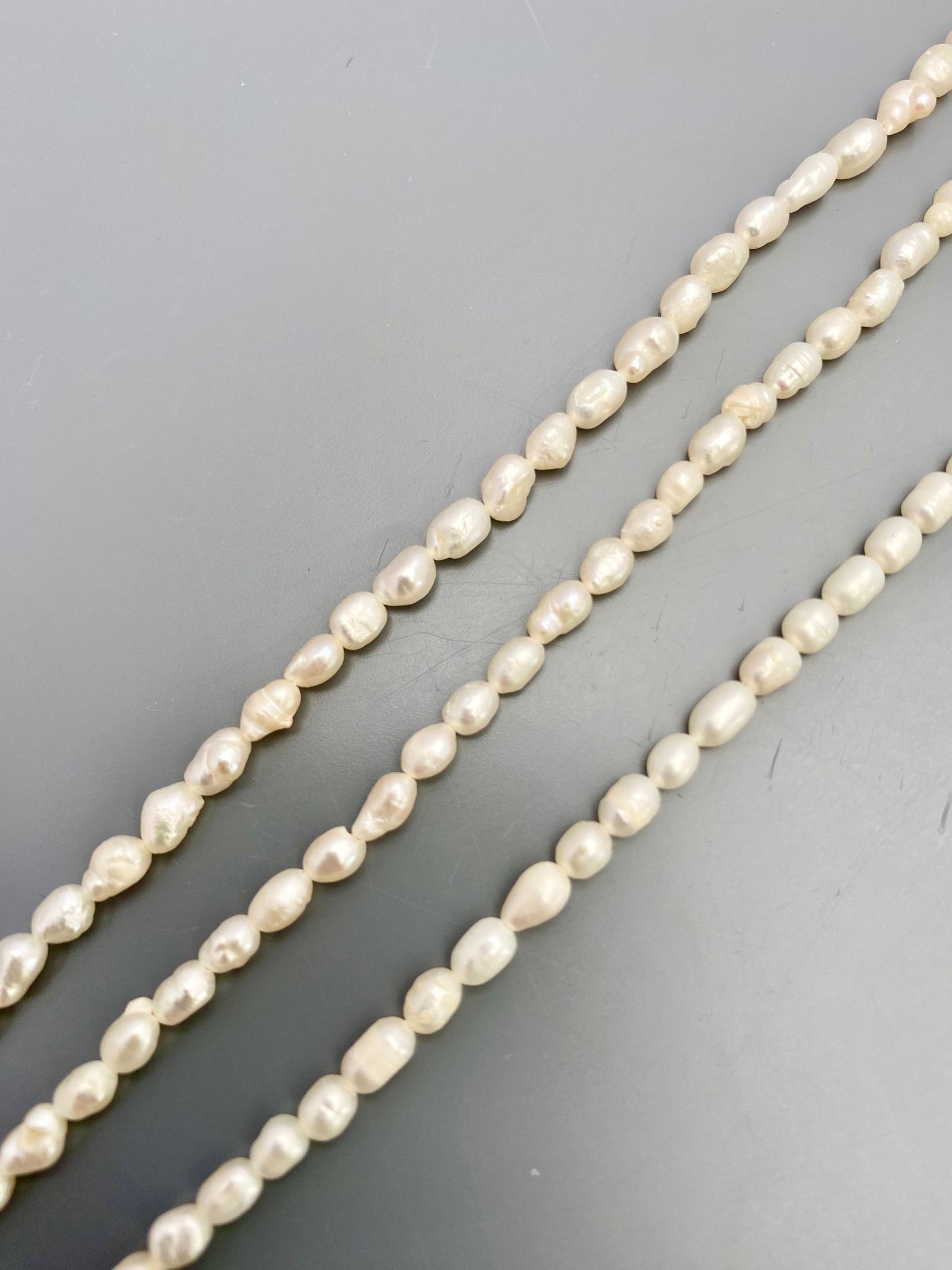 Freshwater rice pearls arranged in a cascading pattern, highlighting their unique textures.