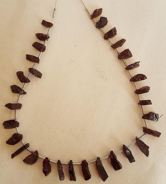 A strand crafted from rough natural garnet gemstone, on a white background,  radiating warmth and elegance.