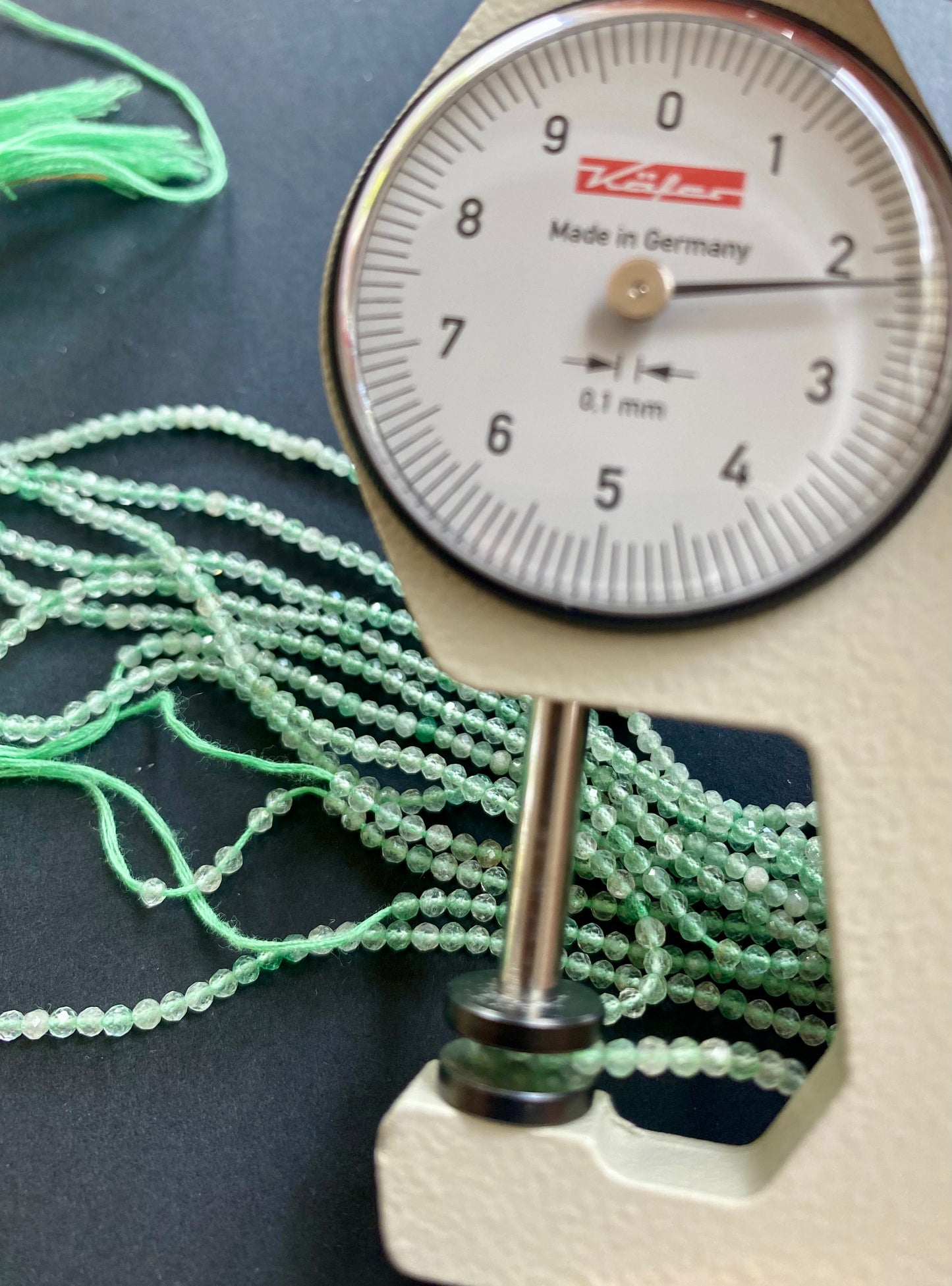 A dial gauge measures the Green Amethyst Faceted Rondelle 2.2mm gemstone.