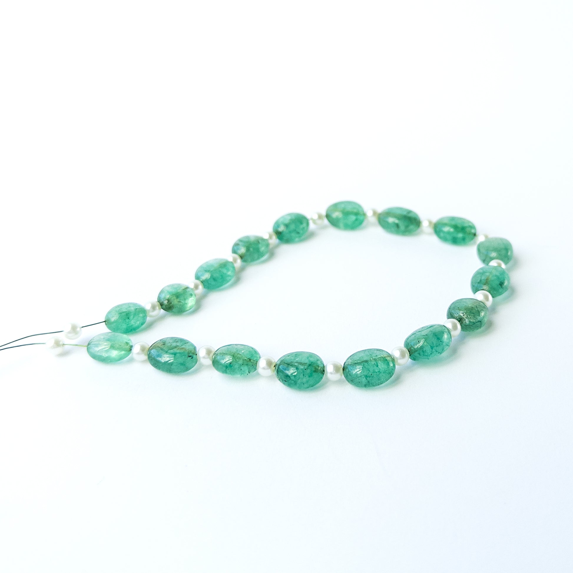Close‑up of Green Beryl and Shell Pearl smooth oval beads showing their polished surface and clarity.