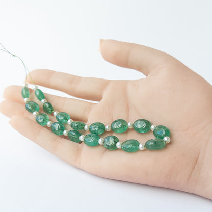 A person holds delicate strands of Green Beryl and Shell Pearl beads, showcasing their smooth oval design.